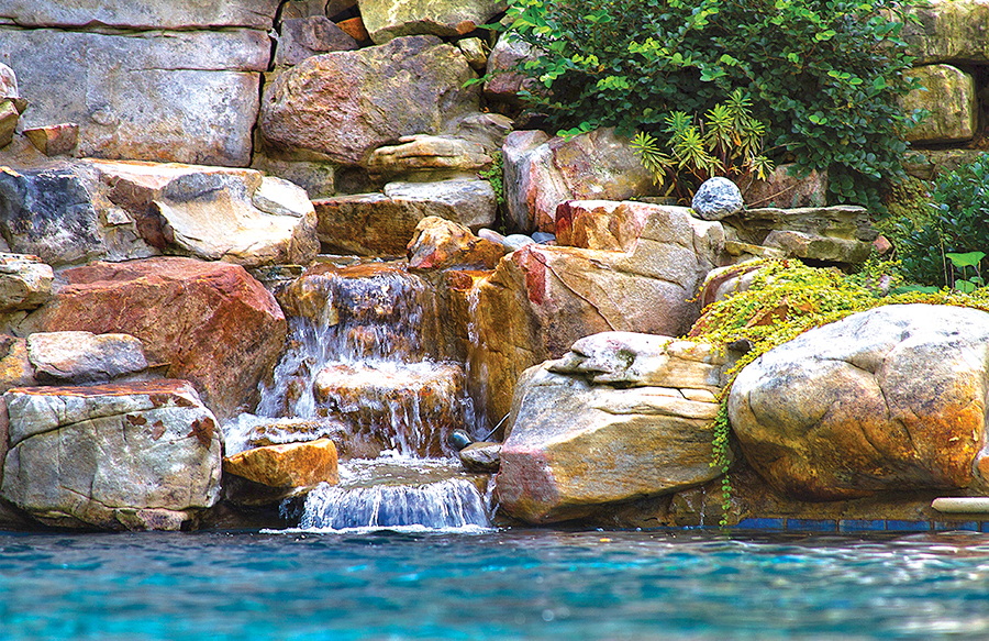 inground pool with rock waterfall