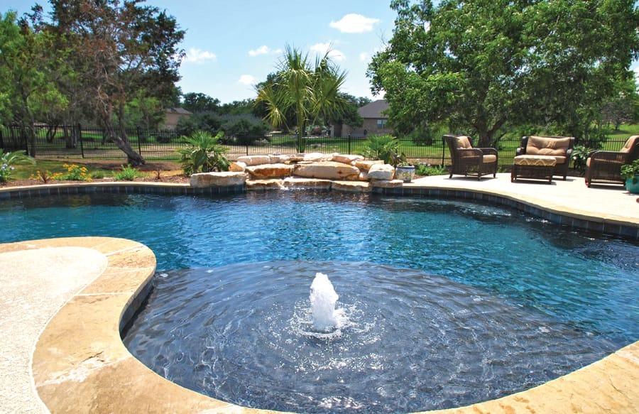 Freeform backyard pool with sun shelf, rock waterfall, and bubbler fountain