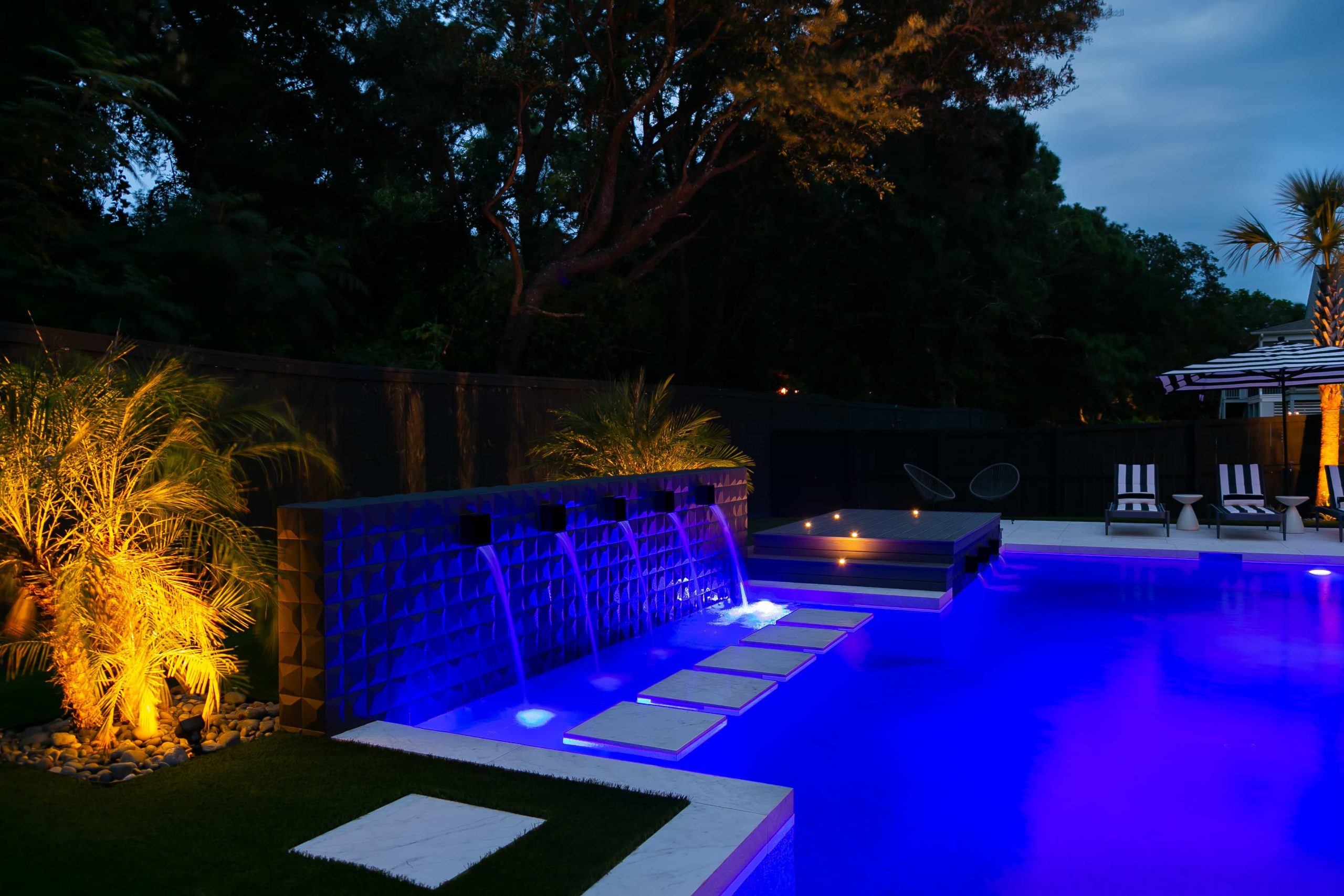 backyard swimming pool with color changing LED lighting at night