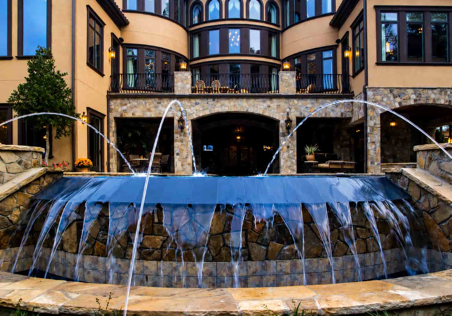 Deck jets and reverse infinity cascade wall on a luxury estate pool at dusk