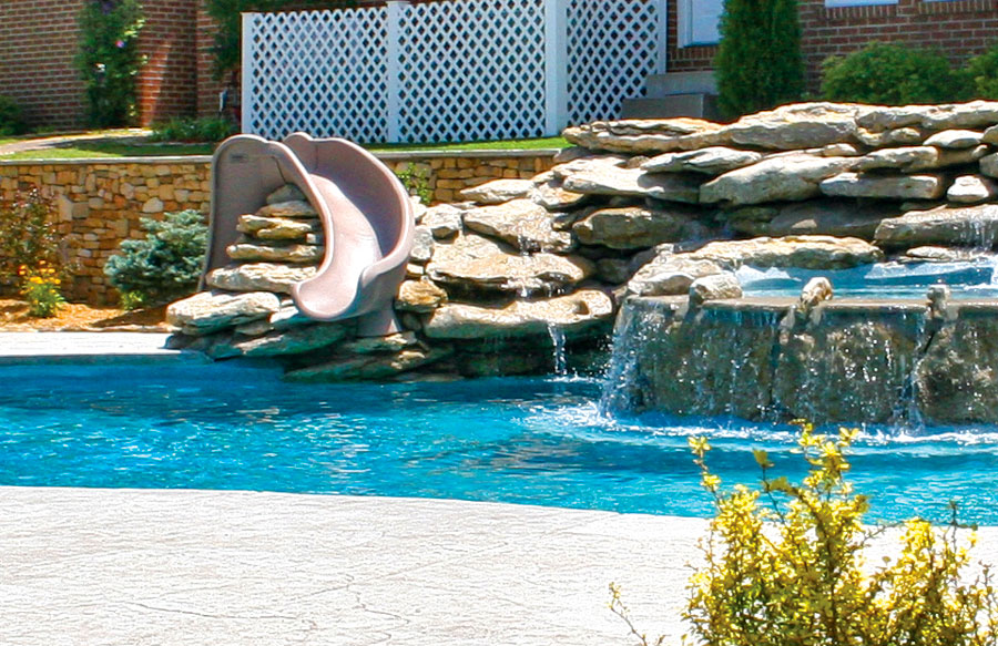 deck-mount-slide-installed-into-rock-waterfall-on-pool