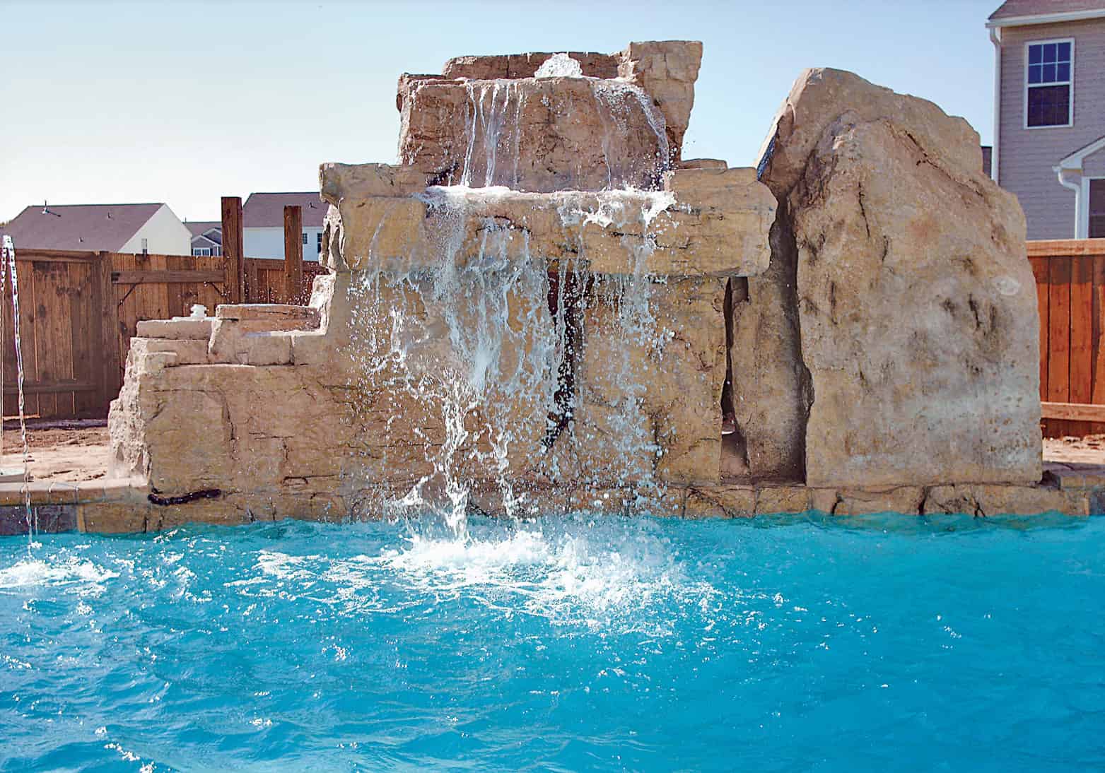 Faux rock grotto waterfall with cave opening and cascading water in a Blue Haven inground pool