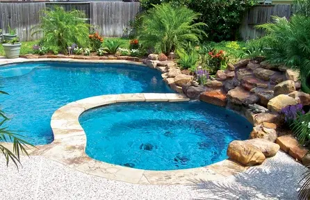 small freeform backyard pool with built-in spa and natural rock landscaping