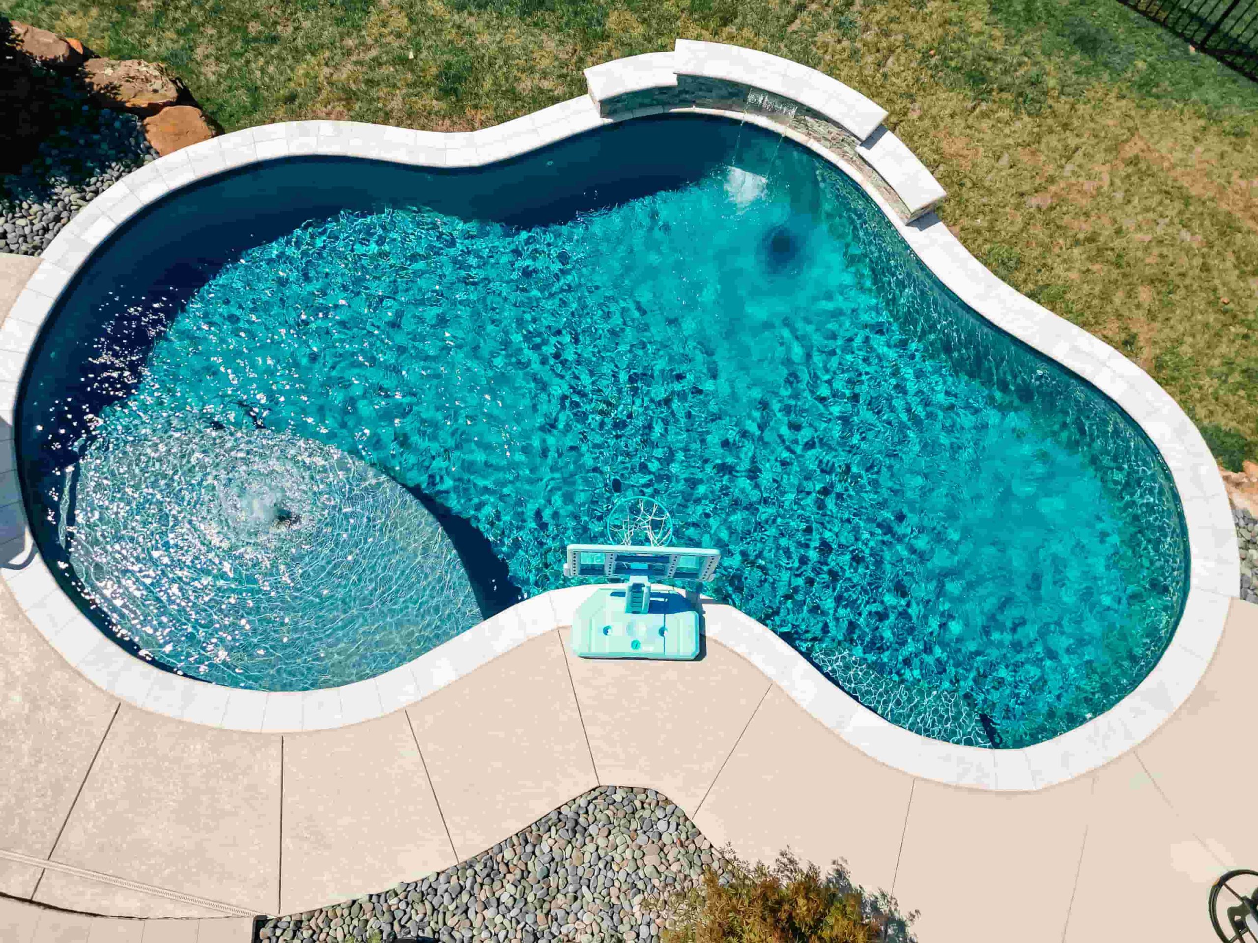 Custom gunite pool with deck jets, sheer descent waterfall, attached spa, and landscaped outdoor living area