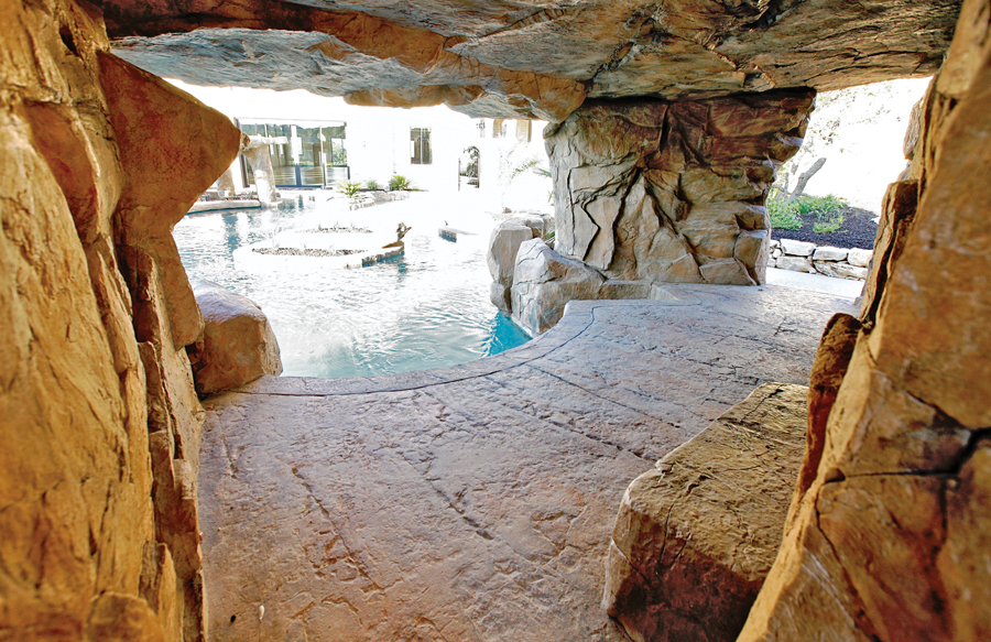 Tropical pool grotto waterfall with natural rock cave and lagoon-style design