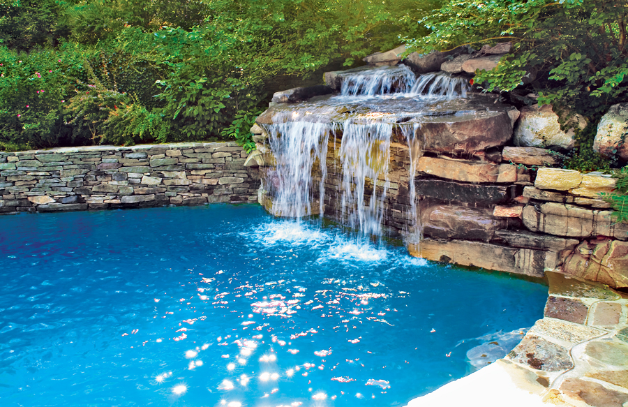 Freeform tropical pool with large natural rock waterfall and palm landscaping