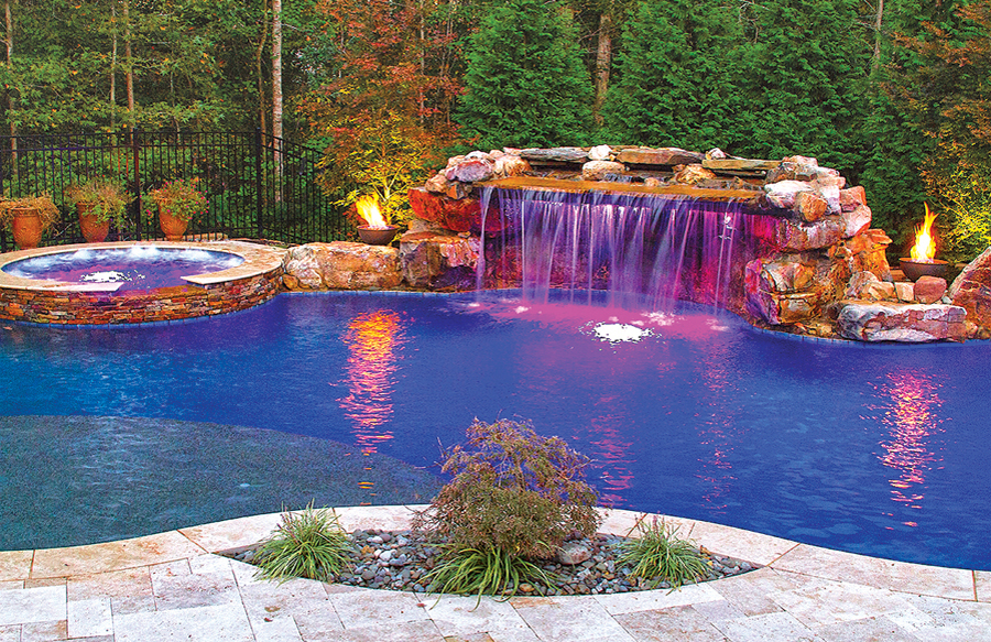 Custom pool with grotto waterfall and LED lighting illuminating cascading water in daytime