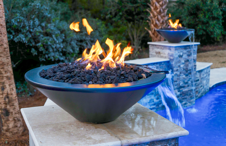 Fire bowls installed along pool edge at night
