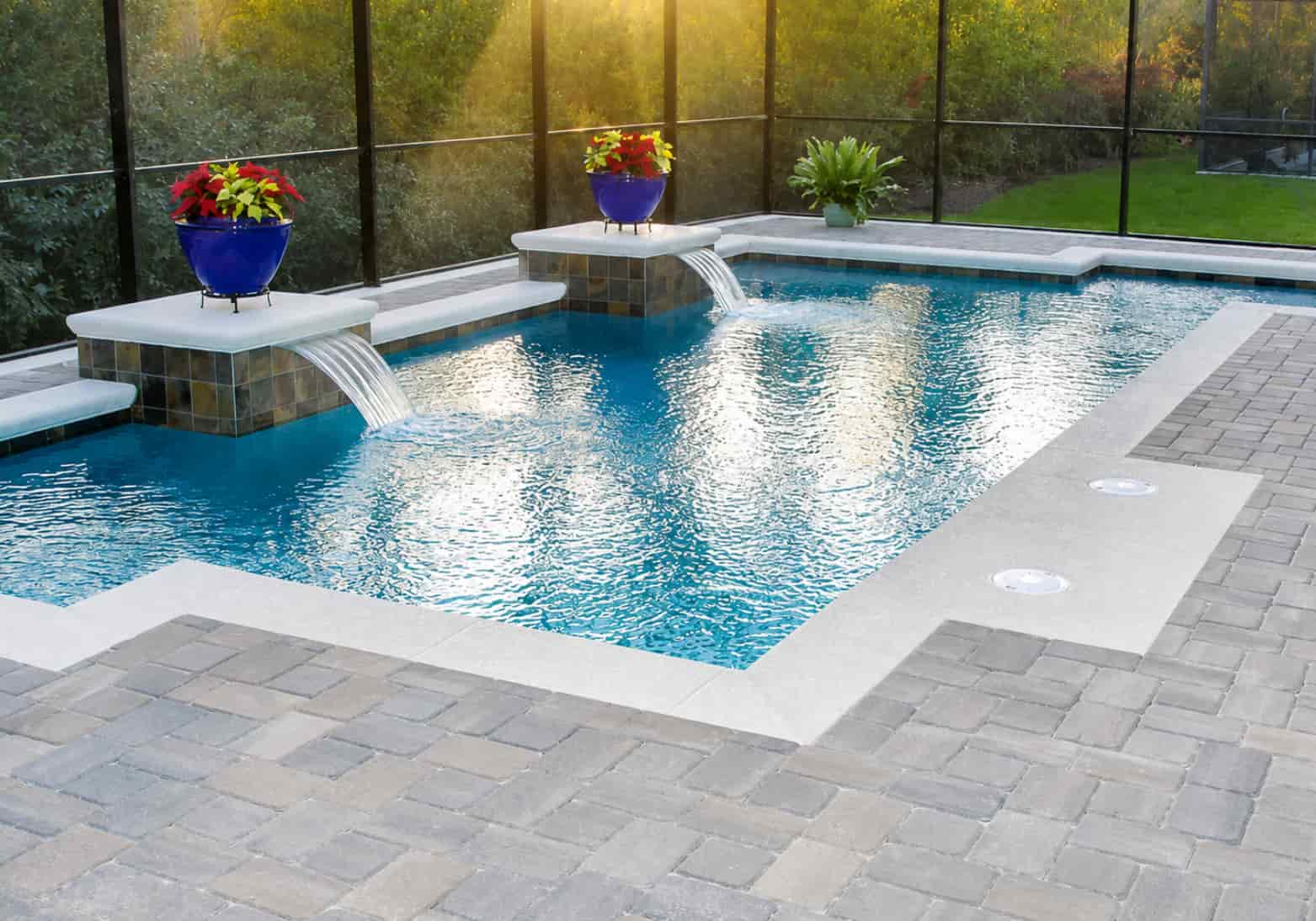 Two sheer descent cascade water features on raised tile pedestals in a screened rectangular pool