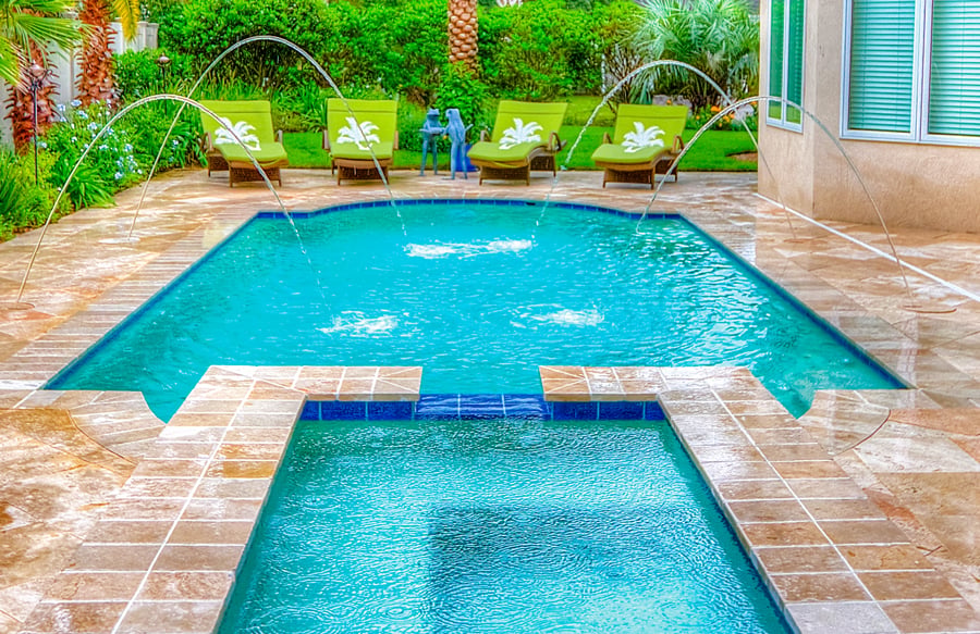 small backyard pool with attached spa, deck jets, and compact patio design