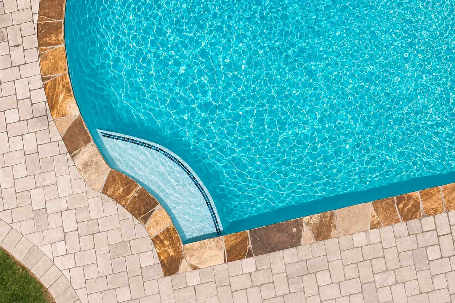 Aerial view of a tanning ledge with mosaic tile accent in a Blue Haven inground pool