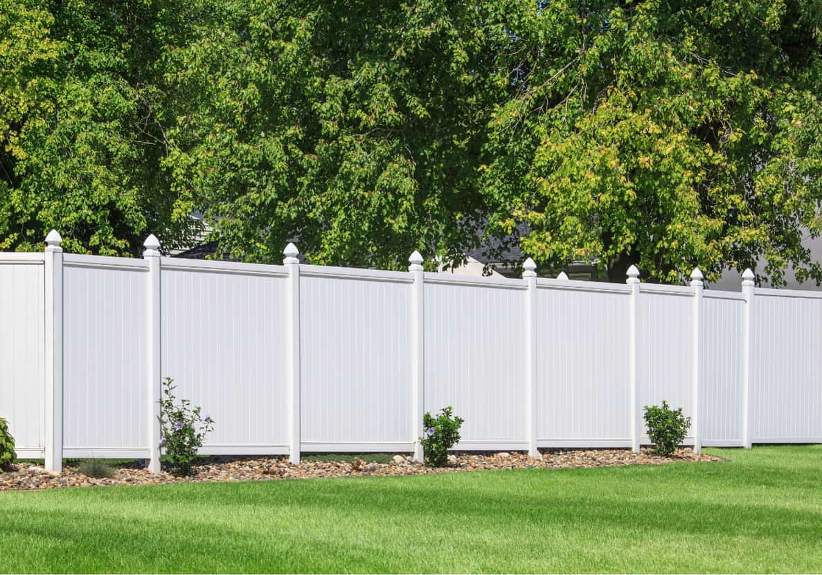 White vinyl privacy fence along a residential backyard lawn